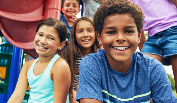 A group of kids sit on a playground at a YMCA youth program. 