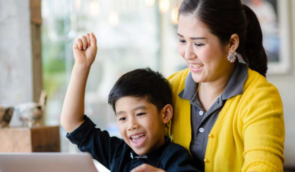 Mother on a computer with son in her lap registering for an after school program