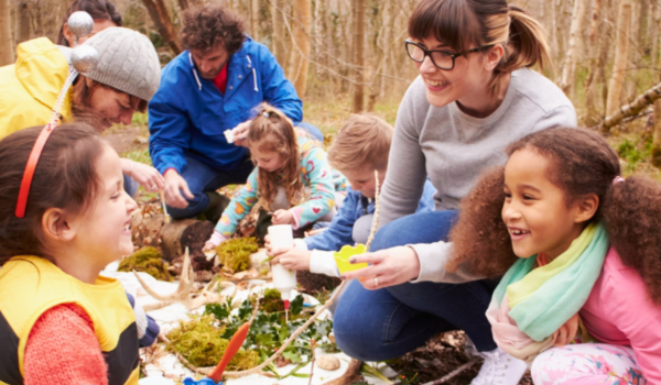 afterschool program teachers with young students outside at a table working on creative project with plants  