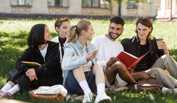 A group of college students sit outside during summer break on campus. 