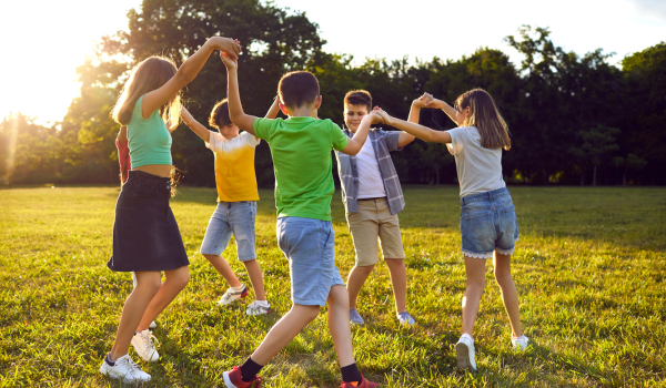 A group of kids play in a circle during a summer youth program. 