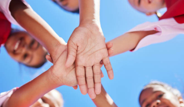 Group of children put their hands together in a circle.