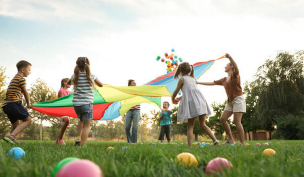 A group of children participate in a parachute game outside. 