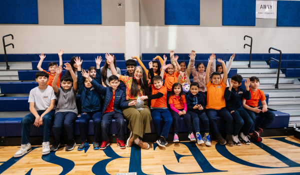 A group of children surround the 2023 Arly Impact Award Winner.