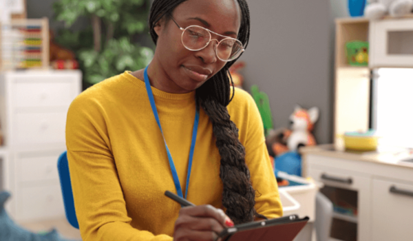 A teacher completes compliance tasks on an ipad in her classroom.
