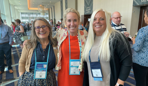 Two Arly team members stand with a customer at the NAYDO conference. 