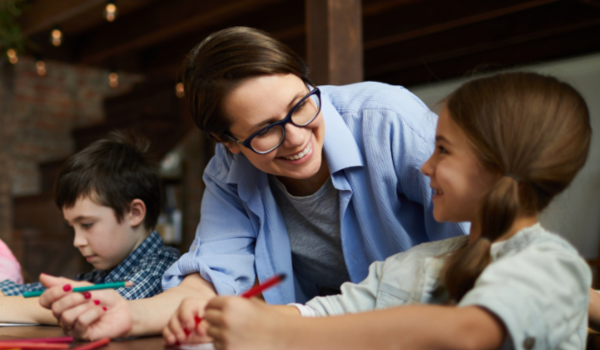 Afterschool teacher sits at a table with a few participants. 