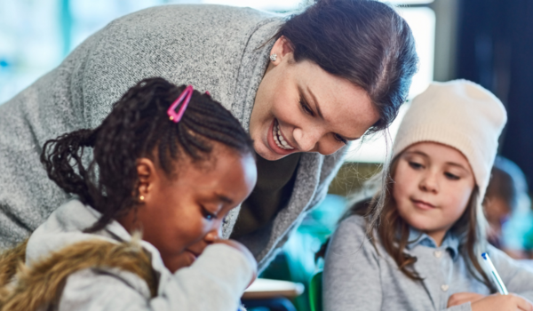 Classroom teacher sits among two students.