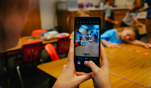 Staff member takes a photo of child for social media during a youth program.